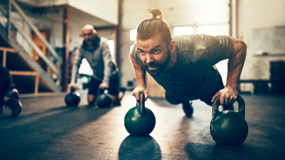 man doing pushups on kettlebells