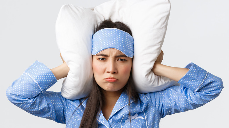 Angry woman holding pillow over ears