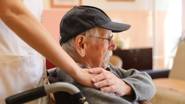 An elderly man sitting in a wheelchair in a nursing home