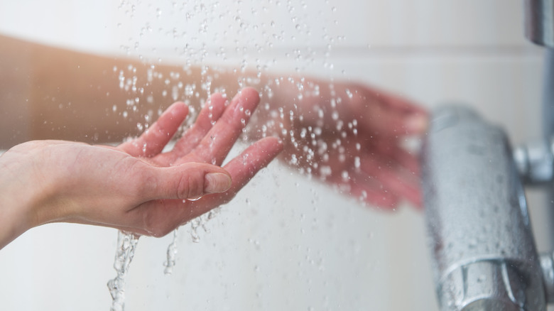 Someone tests shower water temperature