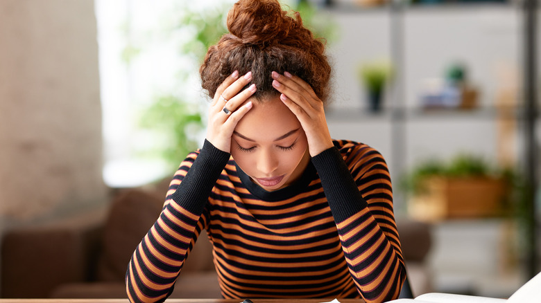 Stressed woman holding head in hands