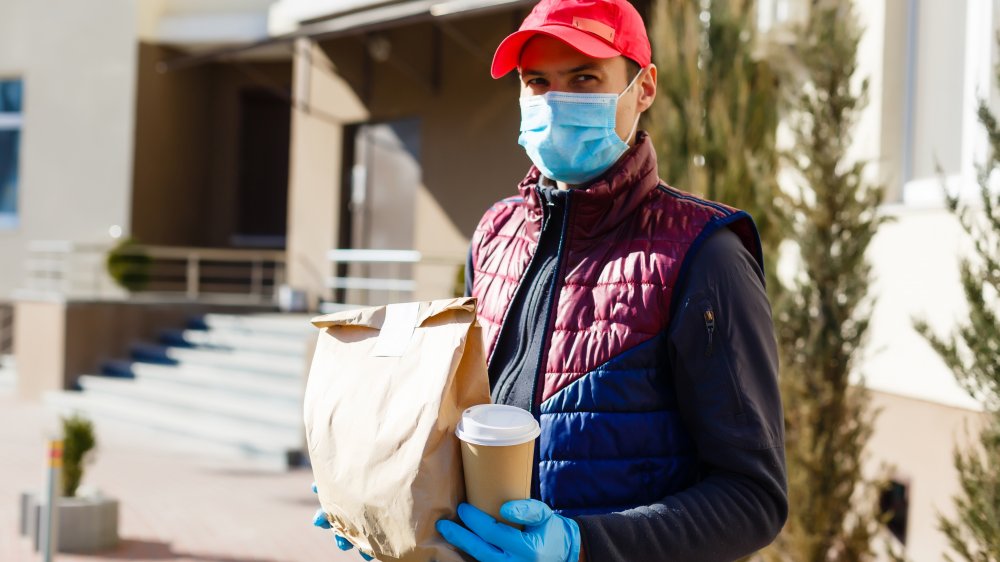 A man carrying food wears a face mask
