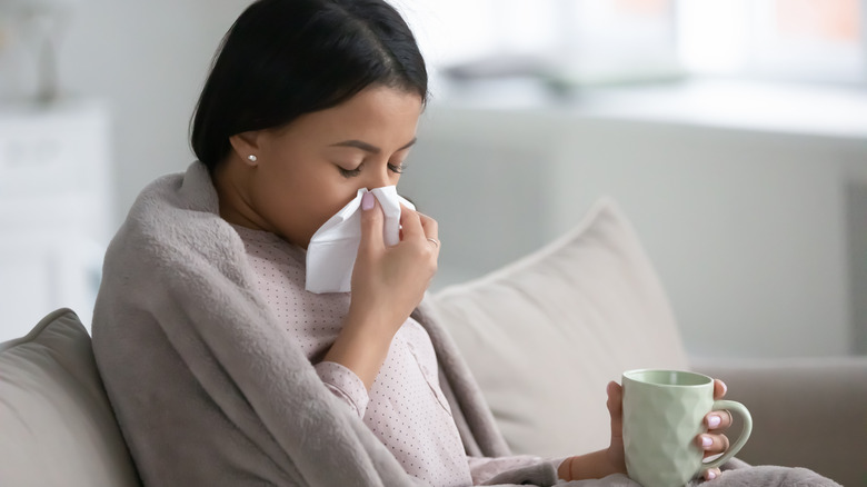 Sick woman blowing nose in tissue