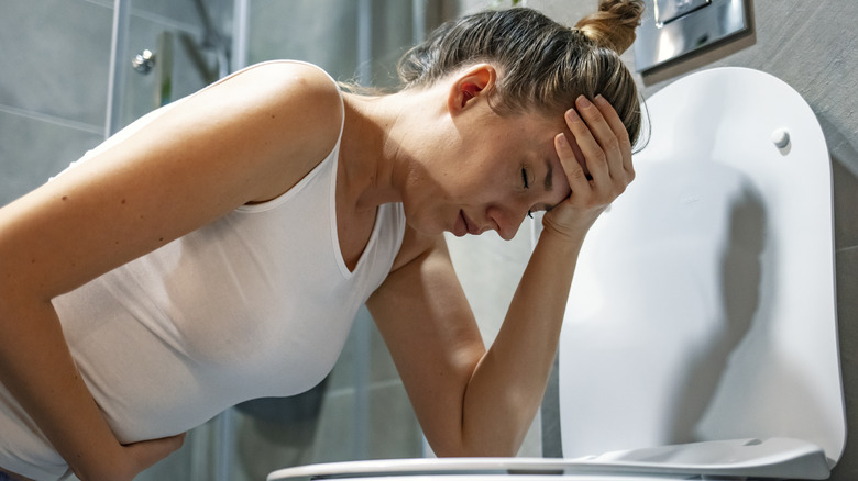 Nauseous woman over toilet