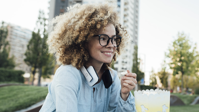 Young woman eating popcorn outside