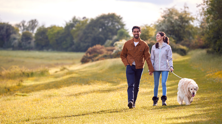 happy couple walks with dog