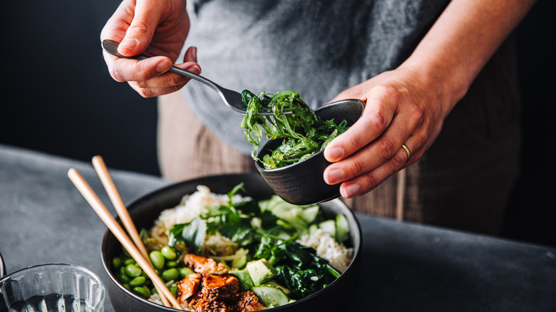 A man adding more greens to his salad