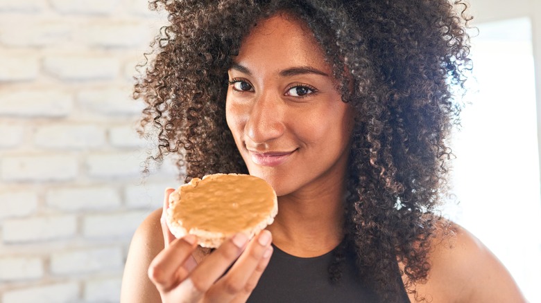 healthy woman eating nut butter on a rice cake