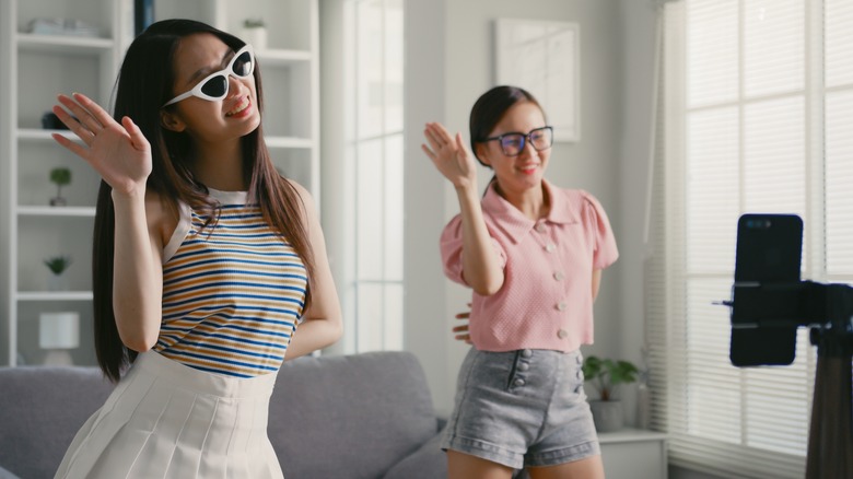 two young girls dancing in front of their mobile phone