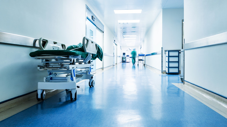 Hospital hallway with gurney and medical professional walkinh