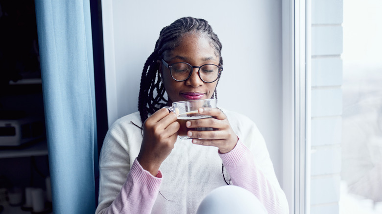 A woman sitting against a wall enjoying tea