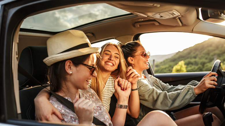 Three friends traveling together in a car going on a road trip