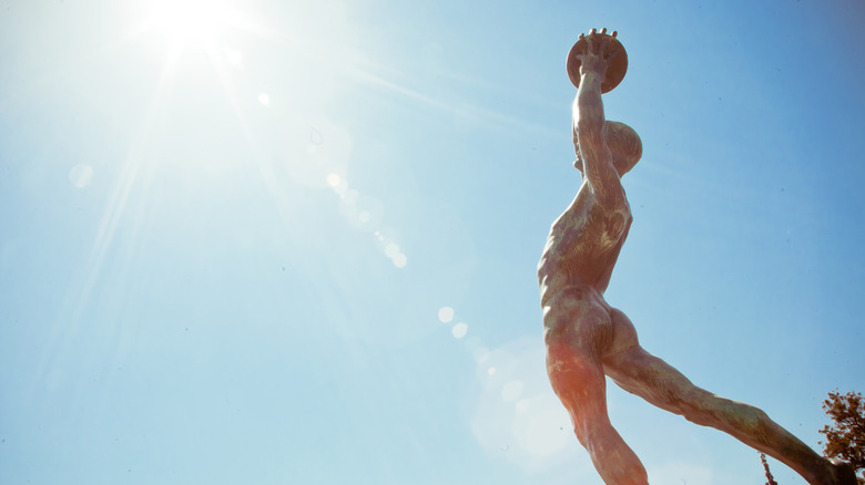 Statue of an ancient athlete raising an exercise ball overhead.