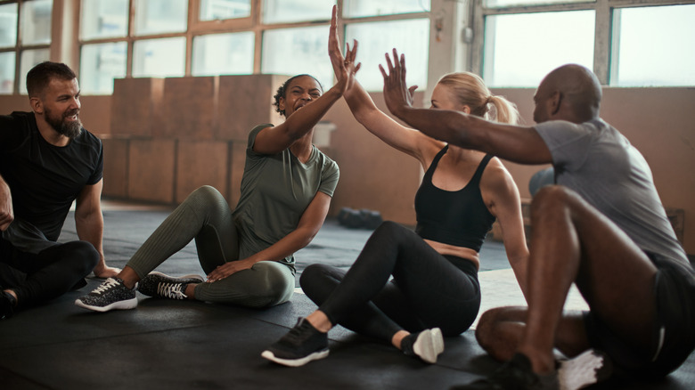 Diverse group laughing and high-fiving at the gym.
