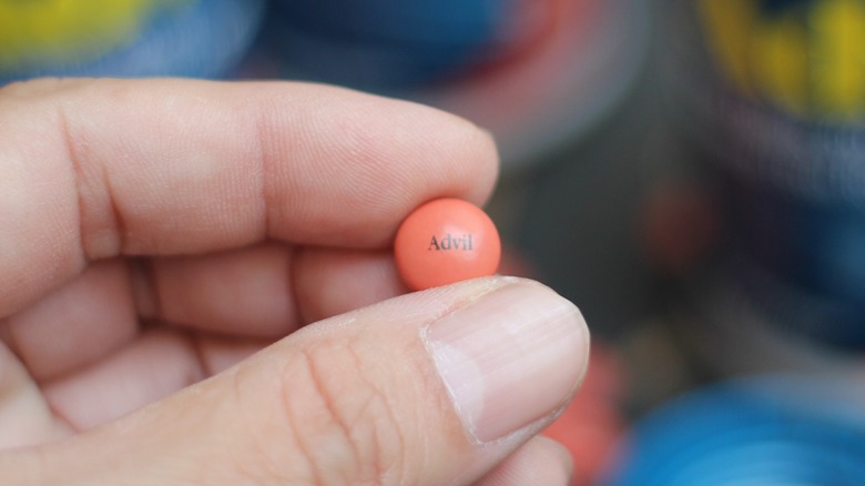 hand holding advil ibuprofen tablet