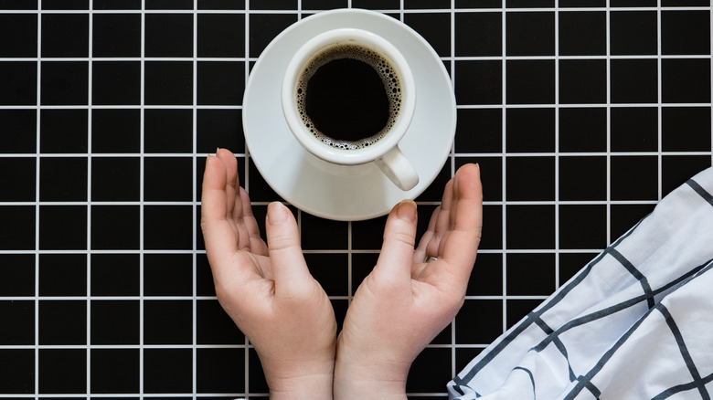 hands reaching for coffee under sheet