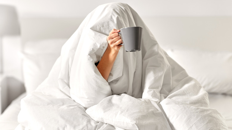 person in bed with mug