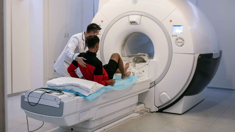 technician helps boy into MRI machine