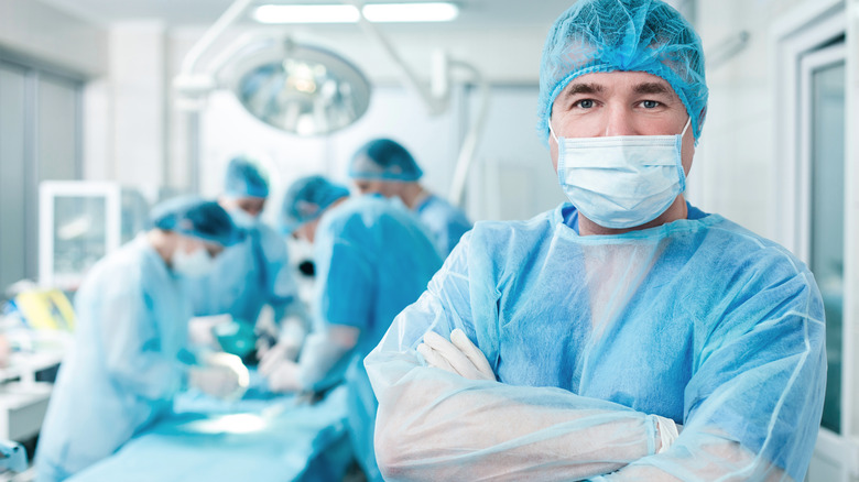 a surgeon stands with his arms crossed as surgery proceeds