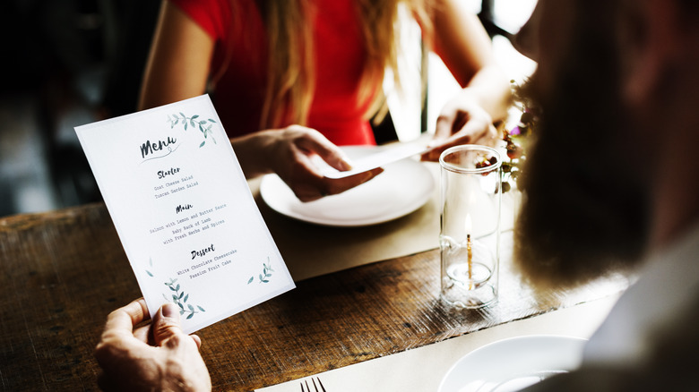 a couple dining at a restaurant looking at the menu 