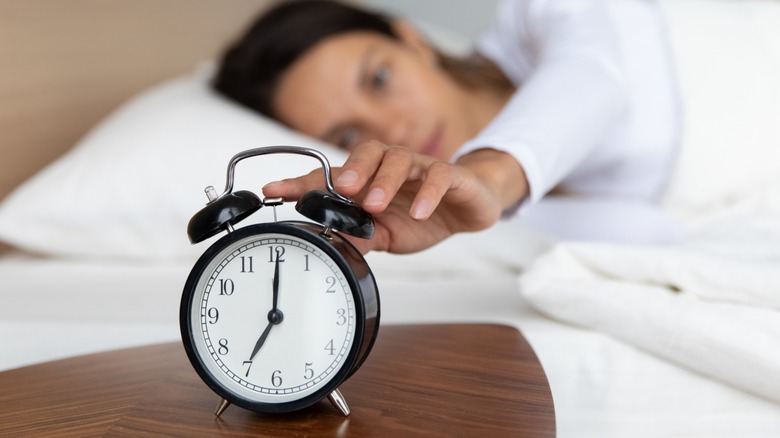 sleepy woman pushing snooze button