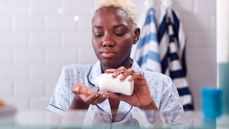 Woman taking medication in bathroom