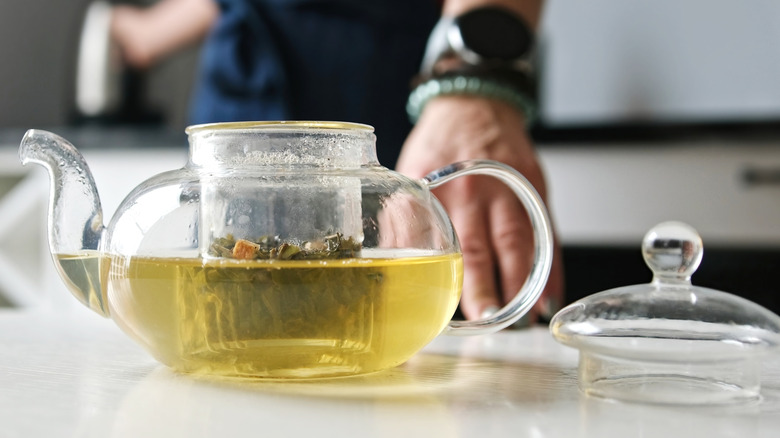 Man preparing green tea in a glass teapot