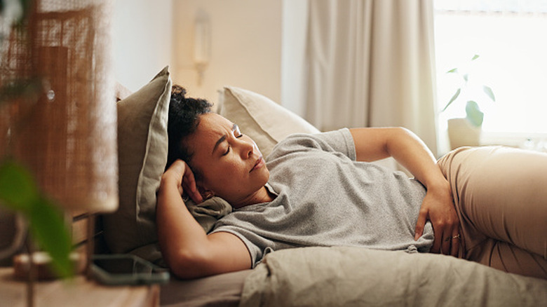 woman lying down with hand on abdomen