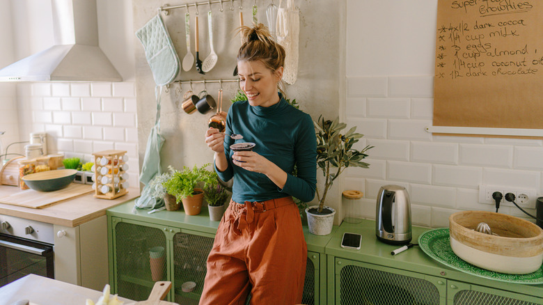 woman eating yogurt and berries in kitchen