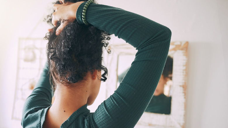 Woman styling hair in updo