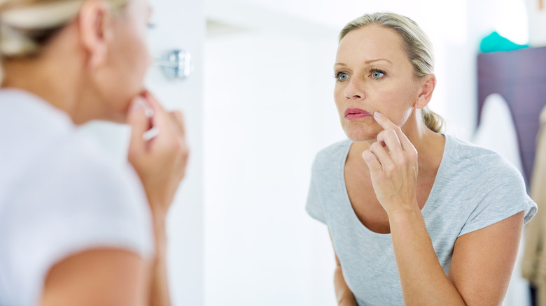Woman inspecting lips in mirror