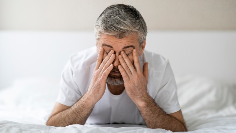 man with head in hands unable to sleep