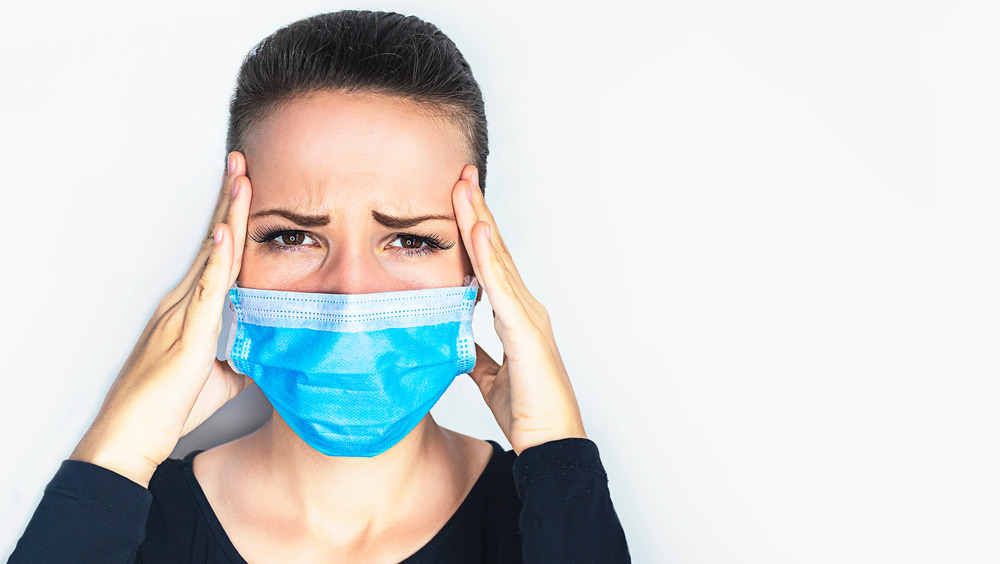 Woman wearing mask holding head