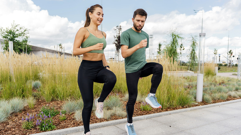 A couple doing high-knees exercise outside