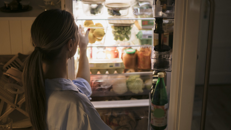 Woman opening fridge at night