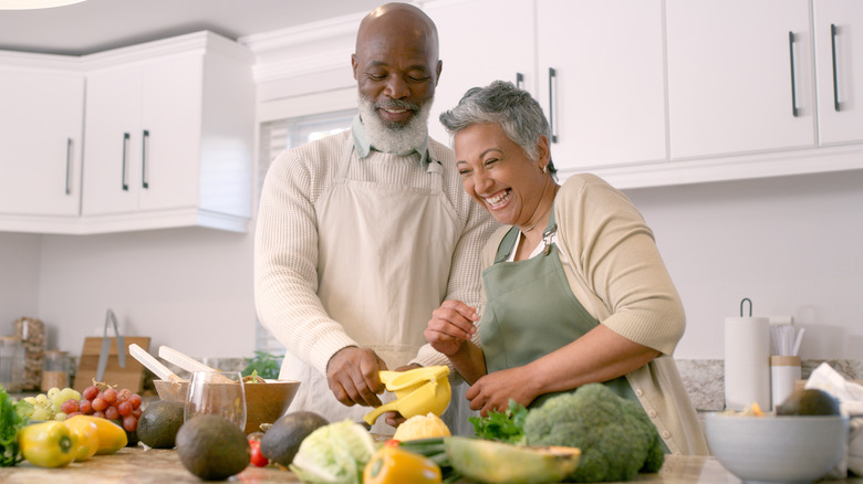 happy couple chopping healthy fruits and vegetables