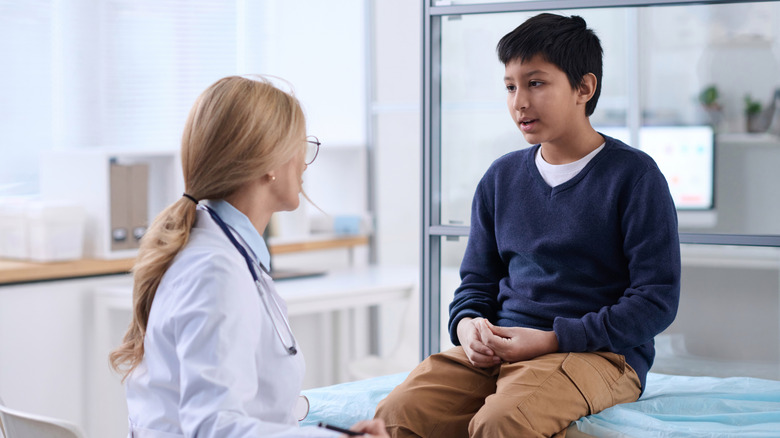 A young boy talking to his doctor in an examination room