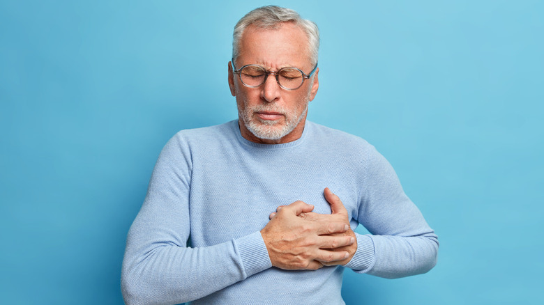 Close up of a man's chest as he clutches his heart which is outlined in red