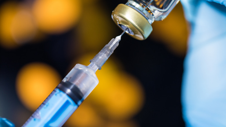 A syringe drawing insulin from a vial