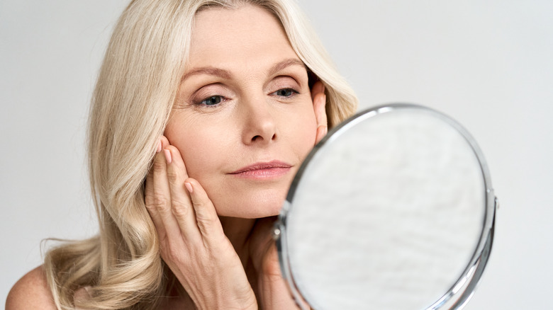 Older woman looking at her skin in the mirror