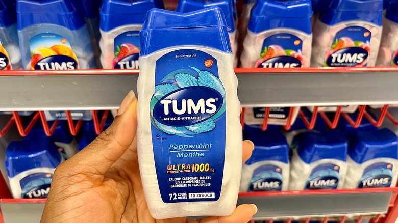 Hand holding container of Tums