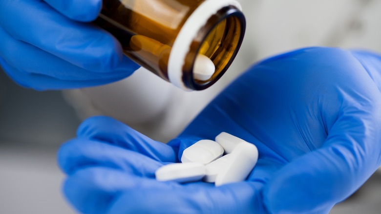 Gloved hands with antibiotic pills
