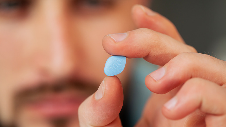 Man with beard holding Viagra pill