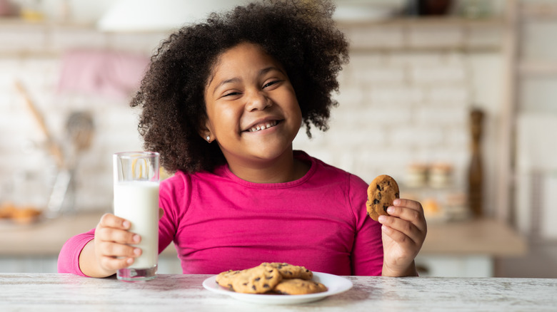 Young girl grinning and eating milk and cookies
