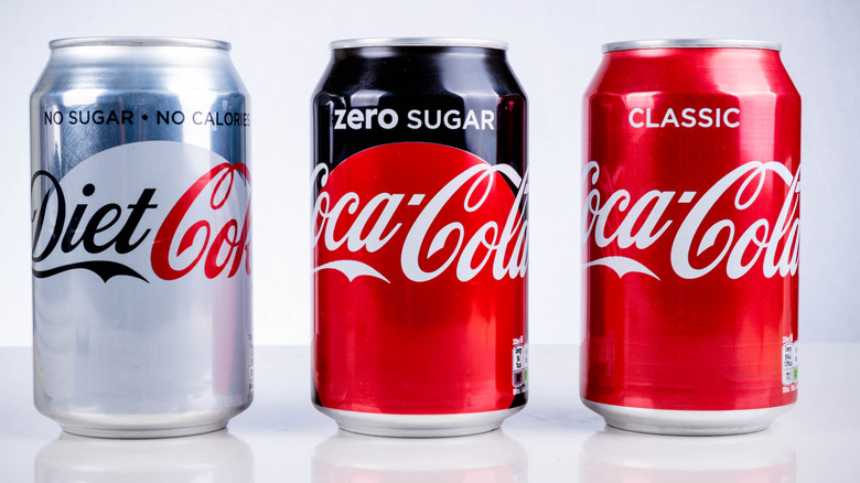 A can of zero sugar Coke between a can of diet Coke and a can of classic Coke