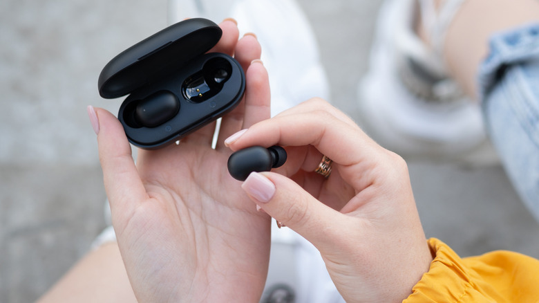 person holding earbuds