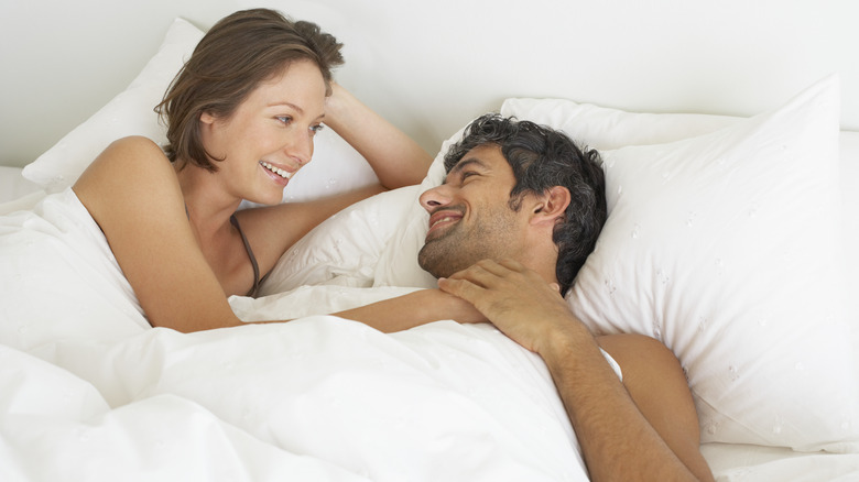 Couple smiling at each other in bed 