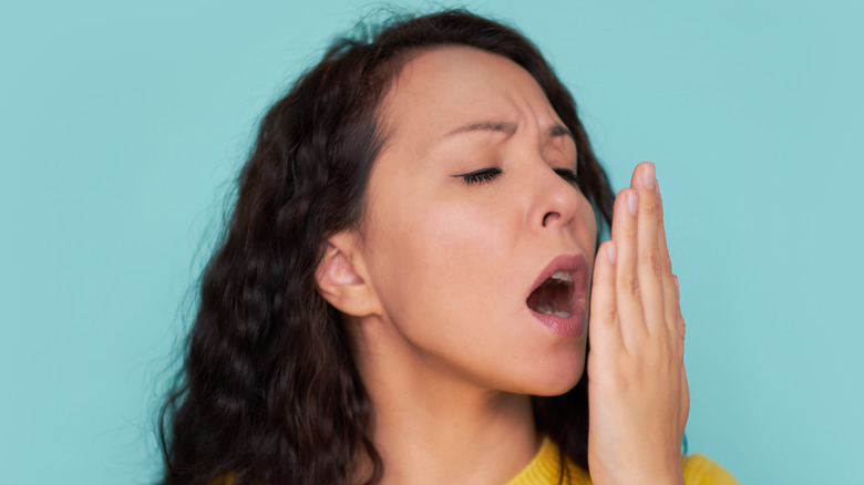 Woman checking the smell of her breath with hand in front of mouth