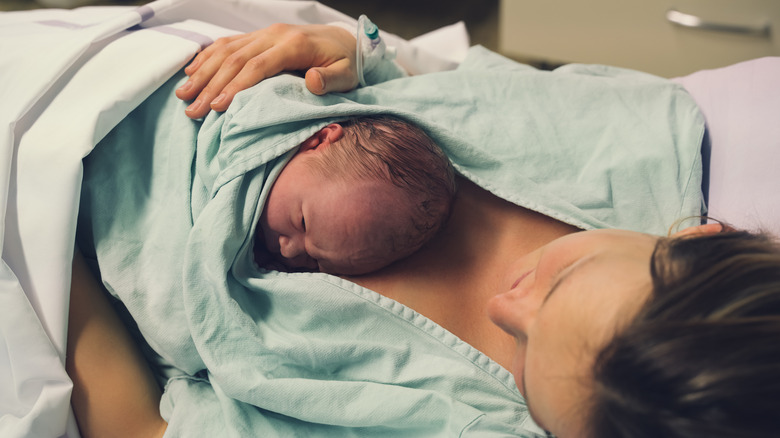 Mother holding her newborn baby on her chest after delivery.