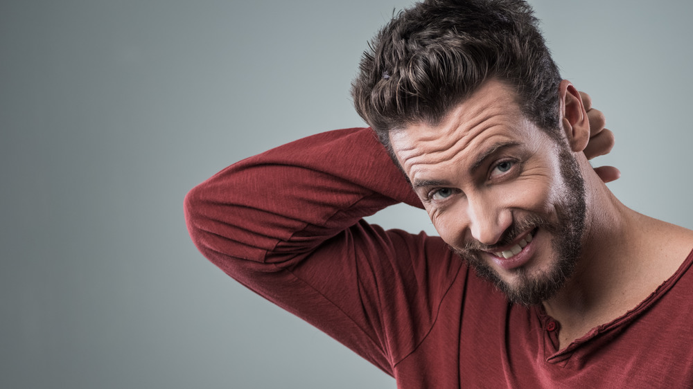 A man looking flushed while touching his hair 